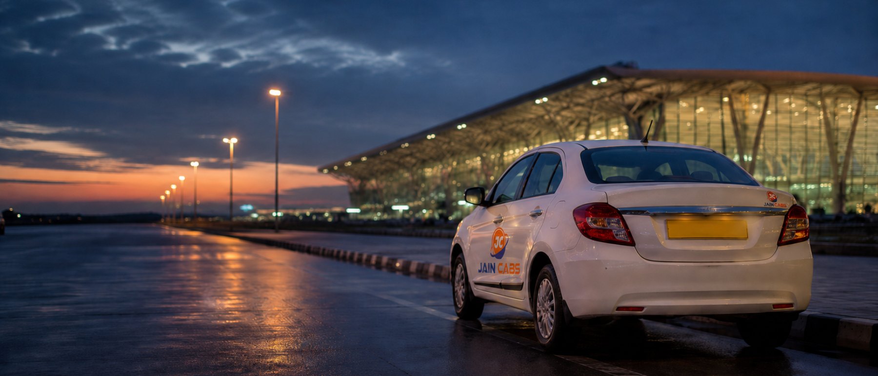 A Jain Cabs taxi waiting at the Kempegowda International Airport terminal kerb at dusk.
