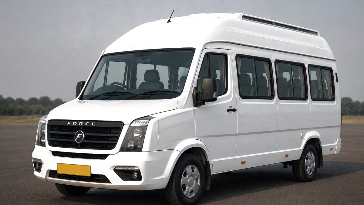 A white Tempo Traveller Non A/C operated by Jain Cabs, 12+1 seats, photographed on a clear road with its yellow commercial number plate visible.